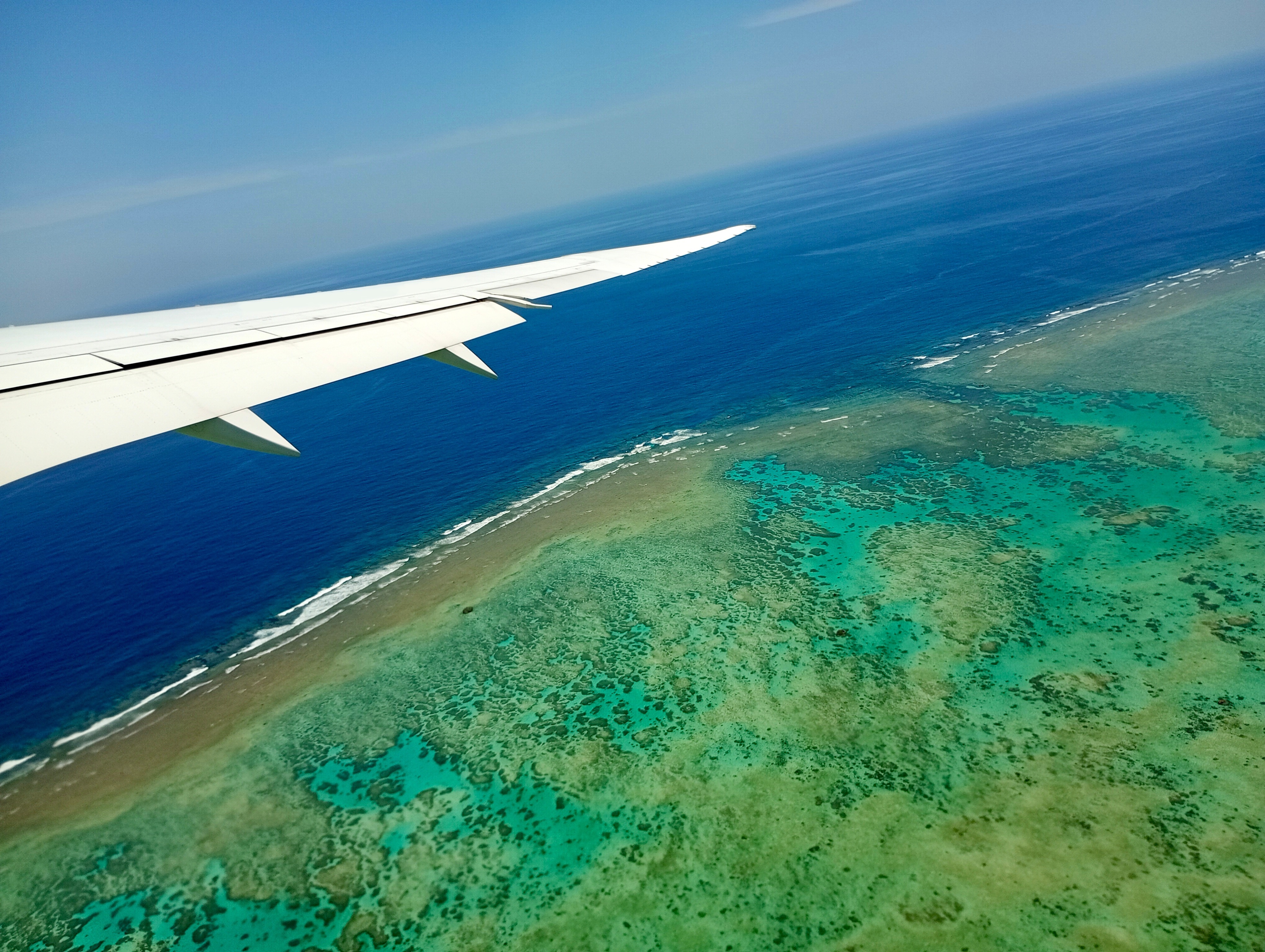 飛行機の窓から見た石垣島周辺のサンゴ礁の海