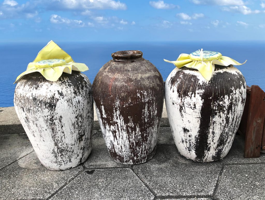 海を望む石段に並ぶ泡盛の古酒甕